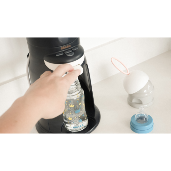 Prístroj na prípravu umelého mlieka s funkciou ohrievania fľaše s nápojom alebo pohára s príkrmom.