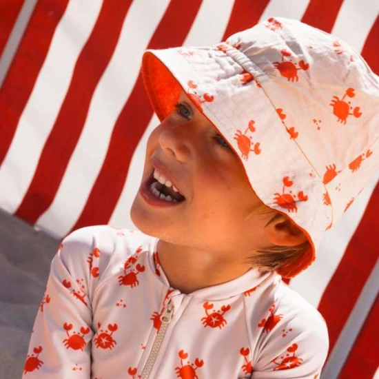 Obojstranný klobúčik pre deti s UPF 50+ – krabí vzor na jednej strane, jednofarebný dizajn na druhej. Široký okraj na ochranu pred slnkom.