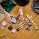 LEGO figúrka Dobbyho stojí na podstavci s menovkou, drží Harryho ponožku v denníku Toma Riddla a vedľa neho levituje pudingový koláč tety Petunie.