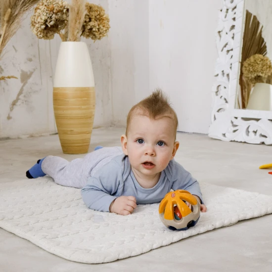 Farebná hrkálka v tvare guličky s otvormi pre jednoduché uchopenie do rúk bábätka