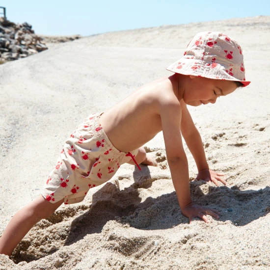 Obojstranný klobúčik pre deti s UPF 50+ – krabí vzor na jednej strane, jednofarebný dizajn na druhej. Široký okraj na ochranu pred slnkom.